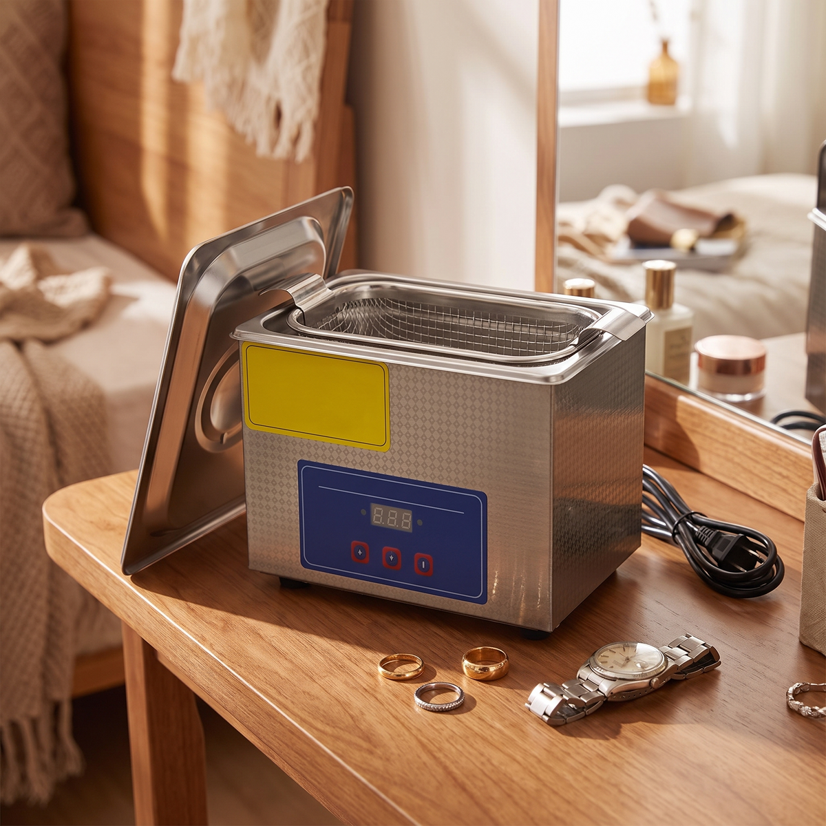an ultrasonic jewelry cleaner open on a dressing table with rings and a watch resting beside it