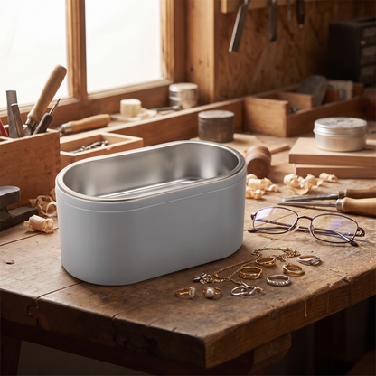 a digital ultrasonic cleaner machine on a workbench with eyeglasses and jewelry beside it